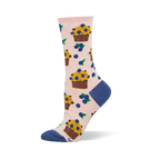 Light pink crew socks patterned with yellow blueberry muffins in brown wrappers and scattered blueberries with green leaves.