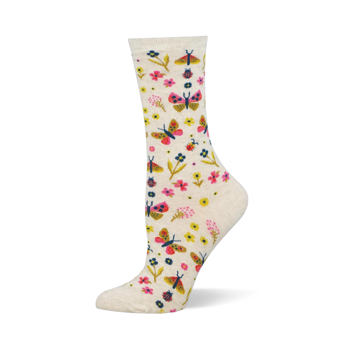Cream crew socks showing a colorful pattern of pink and yellow butterflies, assorted small flowers, and tiny red ladybugs. }}