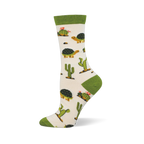 Off-white crew sock with a solid green cuff and matching heel and toe. The pattern features desert tortoises and green cacti.
