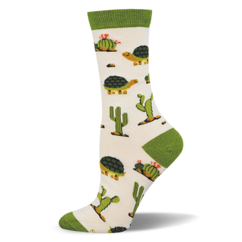 Off-white crew sock with a solid green cuff and matching heel and toe. The pattern features desert tortoises and green cacti.