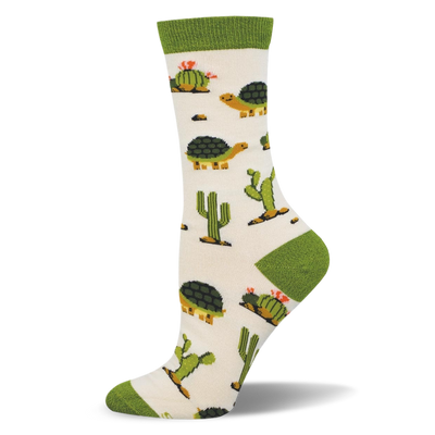 Off-white crew sock with a solid green cuff and matching heel and toe. The pattern features desert tortoises and green cacti.