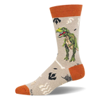Light tan crew sock with a green T-Rex, pale bones, dark footprints, and rust-orange accents.