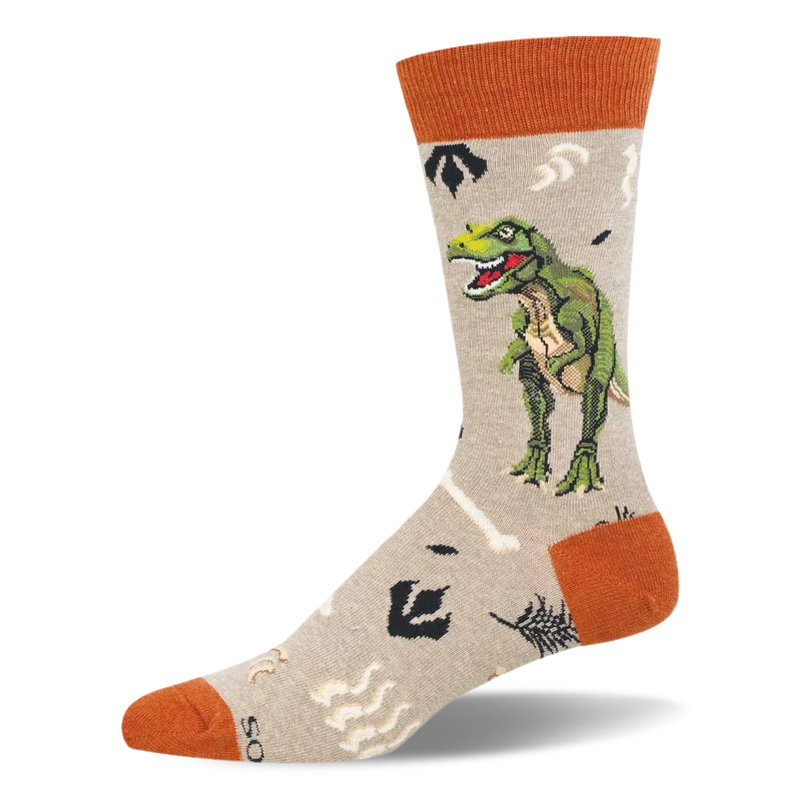 Light tan crew sock with a green T-Rex, pale bones, dark footprints, and rust-orange accents.