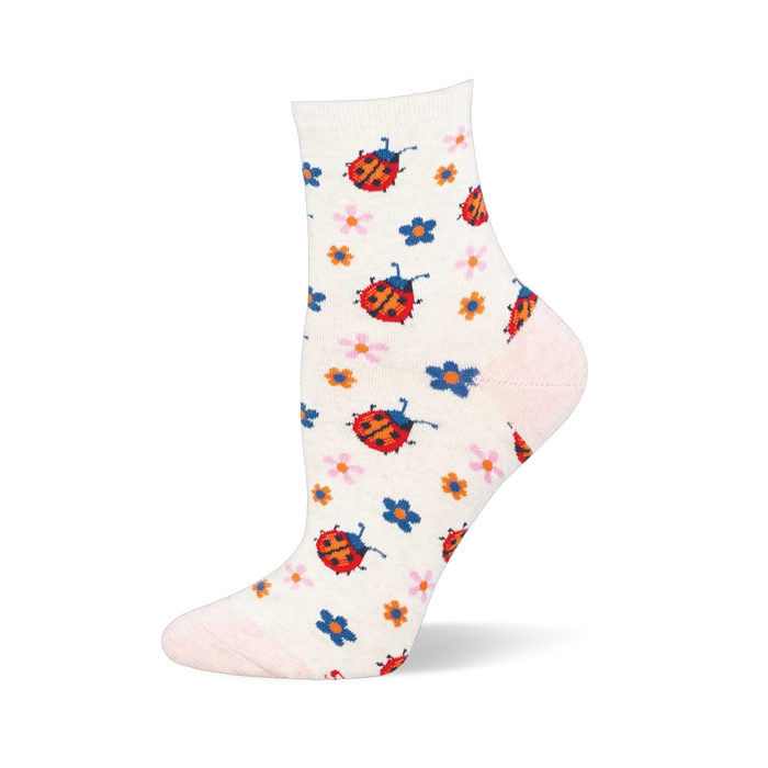Close up of the sock fabric showing a bright red ladybug with black spots and antennae next to small knit flowers.