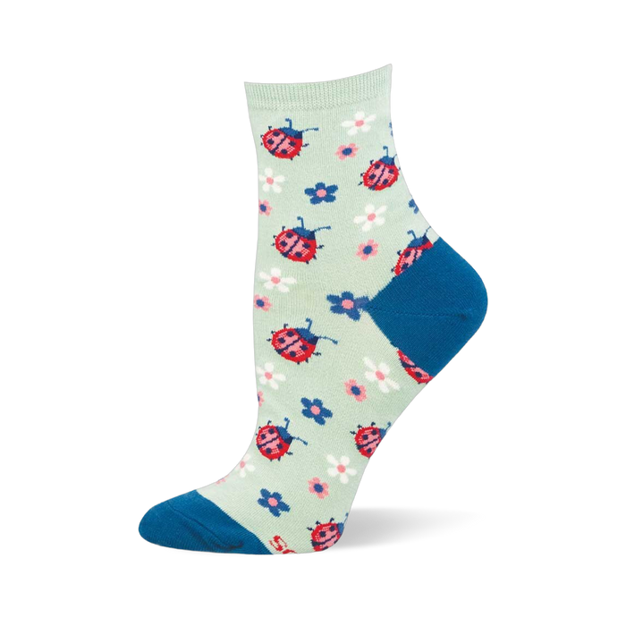 Light mint green crew sock featuring a pattern of red ladybugs and colorful small flowers, with a dark blue toe and heel.