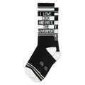 A black crew sock with white text "I LOVE COCK AND HATE THE GOVERNMENT" on a white stripe, black and white stripes. White heel/toe.
