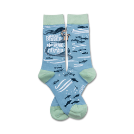 light blue socks with a green cuff. pattern of dark blue fish and mermaid with black hair and green tail. text reads 'kinda pissed about not being a mermaid.'   