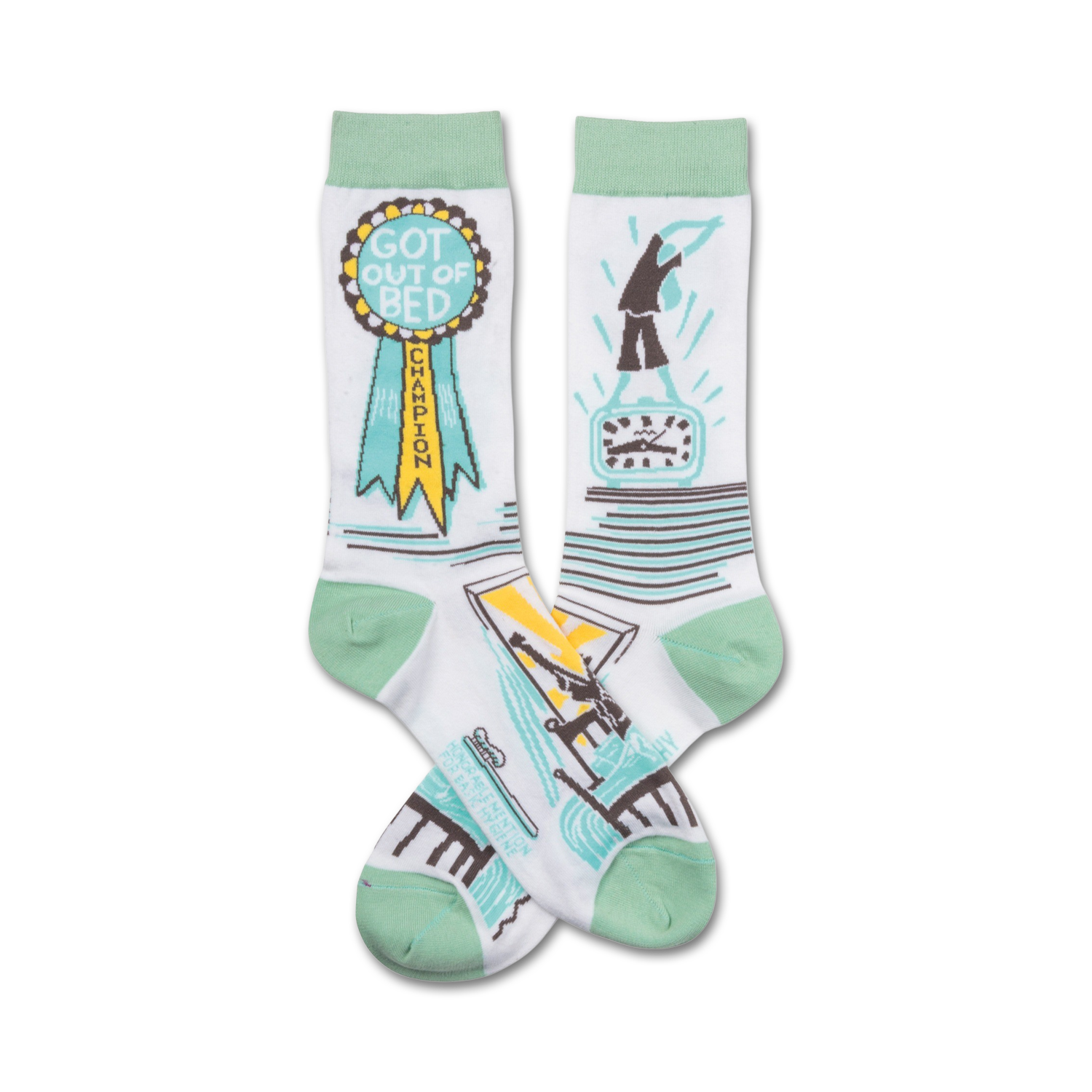 Pair of white crew socks with mint green cuffs. One sock features a 'Got Out of Bed Champion' ribbon; the other shows a figure jumping out of bed next to a clock.