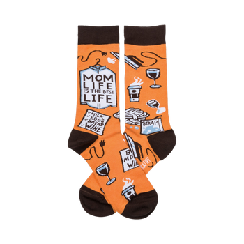 A pair of orange crew socks with a brown cuff. The socks show illustrations of coffee, wine, laundry, and a shopping list that says 'Mom Life is the Best Life'.