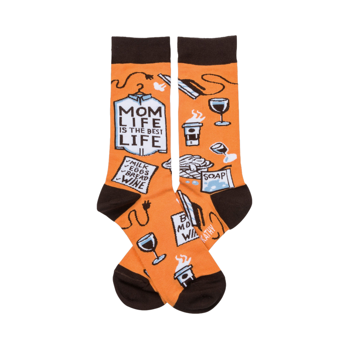 A pair of orange crew socks with a brown cuff. The socks show illustrations of coffee, wine, laundry, and a shopping list that says 'Mom Life is the Best Life'. }}