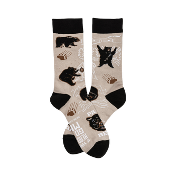 A pair of beige crew socks with a playful design featuring black bears, paw prints, and mountain outlines. The cuffs are black.
