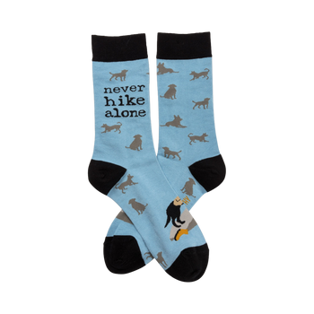 Crew socks in light blue with a repeating pattern of gray dog silhouettes. The text 'Never Hike Alone' is visible on one sock.