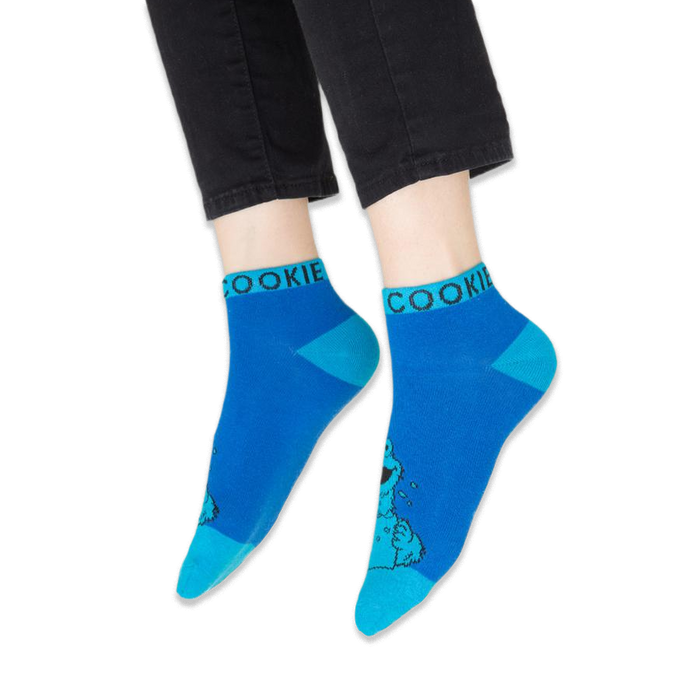 Detail view of the green Oscar the Grouch sock showing the character wearing a book as a hat.