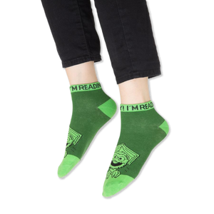 Focus on the blue contrasting cuff of the Cookie Monster sock with partial text visible.