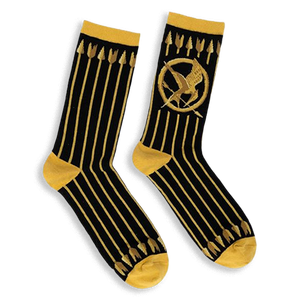 Black crew socks featuring vertical gold arrows, a gold Mockingjay symbol, and contrasting gold cuffs and toe blocks.