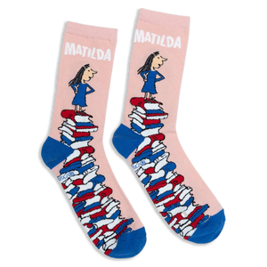 Pink crew socks with blue heels and toes, featuring Matilda standing on a giant tower of colorful books.