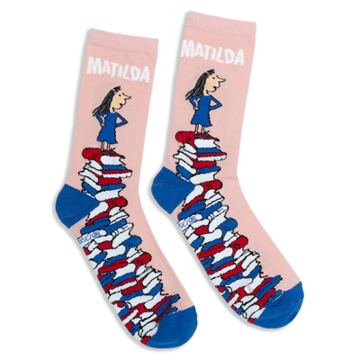 Pink crew socks with blue heels and toes, featuring Matilda standing on a giant tower of colorful books.