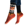 Person wearing the black and orange Read Banned Books socks, showing the white text and eye graphic facing forward.