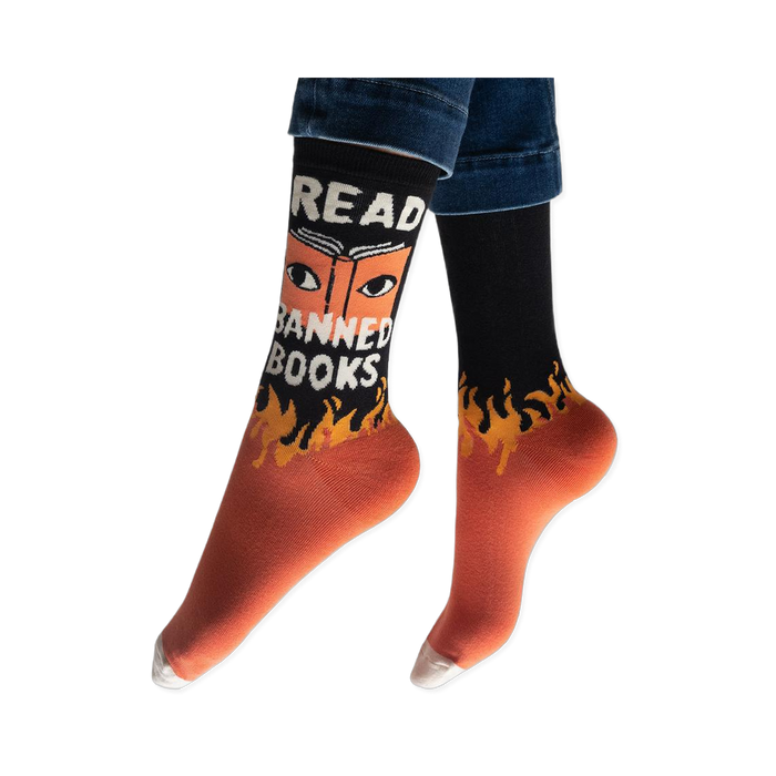 Person wearing the black and orange Read Banned Books socks, showing the white text and eye graphic facing forward.