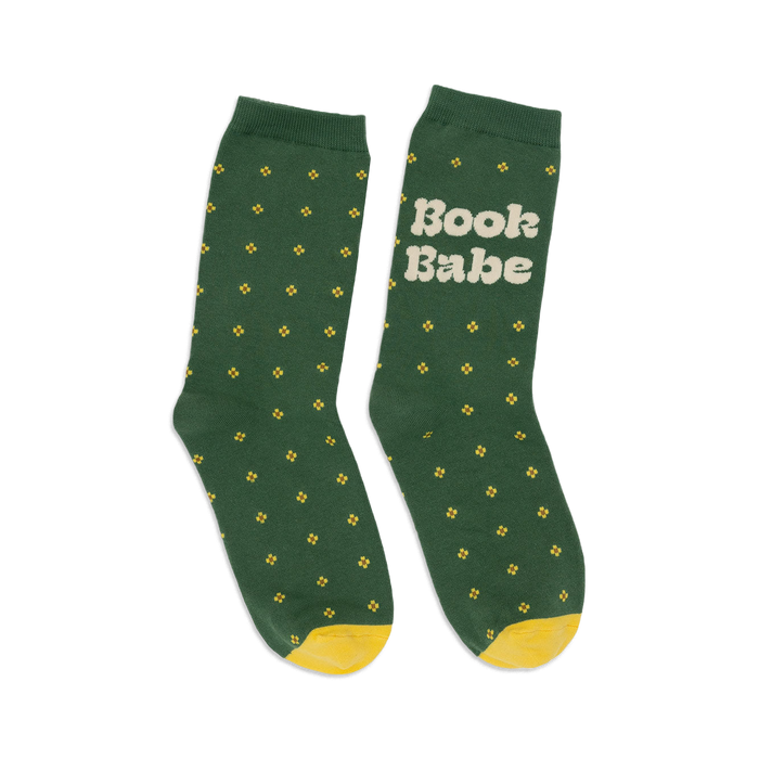 Pair of women's crew socks in forest green with small yellow flower pattern and 'Book Babe' text on one sock. Yellow heel and toe.