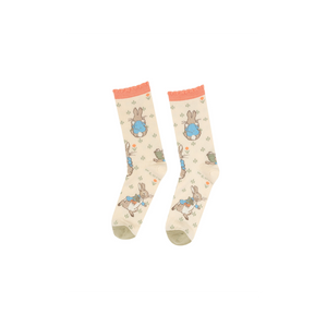 Pair of Peter Rabbit crew socks, light beige with peach ruffled cuffs and olive green toes, laid flat on a white background.