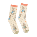 Pair of Peter Rabbit crew socks in light beige, with peach ruffled cuffs and olive green toes, standing upright.