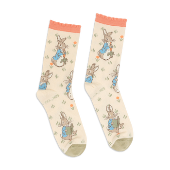 Pair of Peter Rabbit crew socks in light beige, with peach ruffled cuffs and olive green toes, standing upright.