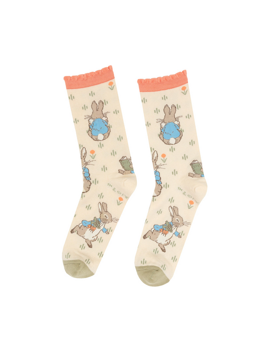 Pair of Peter Rabbit crew socks, light beige with peach ruffled cuffs and olive green toes, laid flat on a white background.