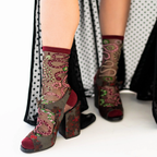 Close up of legs wearing sheer snake and floral socks paired with chunky floral print open-toe platform heels.