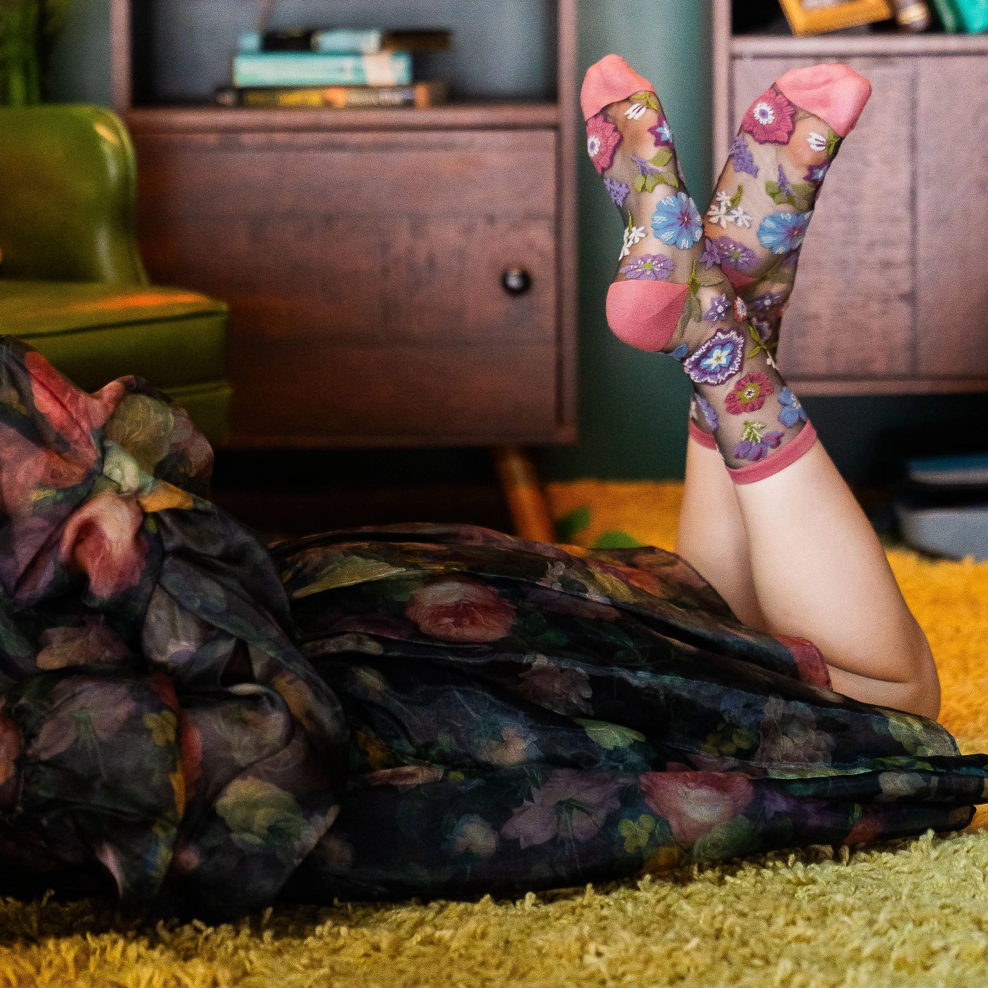 Close up of sheer mesh socks on feet in dark heels highlighting the transparent fabric and colorful woven floral pattern