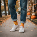 Model wearing candy corn crew socks with cuffed jeans & white sneakers on an autumn sidewalk. [lf]