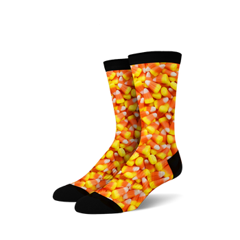 A pair of crew socks covered in a candy corn print. The socks are predominantly orange, yellow, and white, with a black cuff.