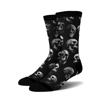 Pair of black crew socks with a repeating grayscale skull pattern.