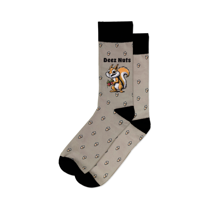 A pair of socks with a pattern of brown acorns on a light gray background. The top of the sock is black with white text that reads 