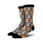 Pair of crew socks, dark grey with orange and white 'It's Leg Day' text and chicken leg illustrations repeating across the fabric.