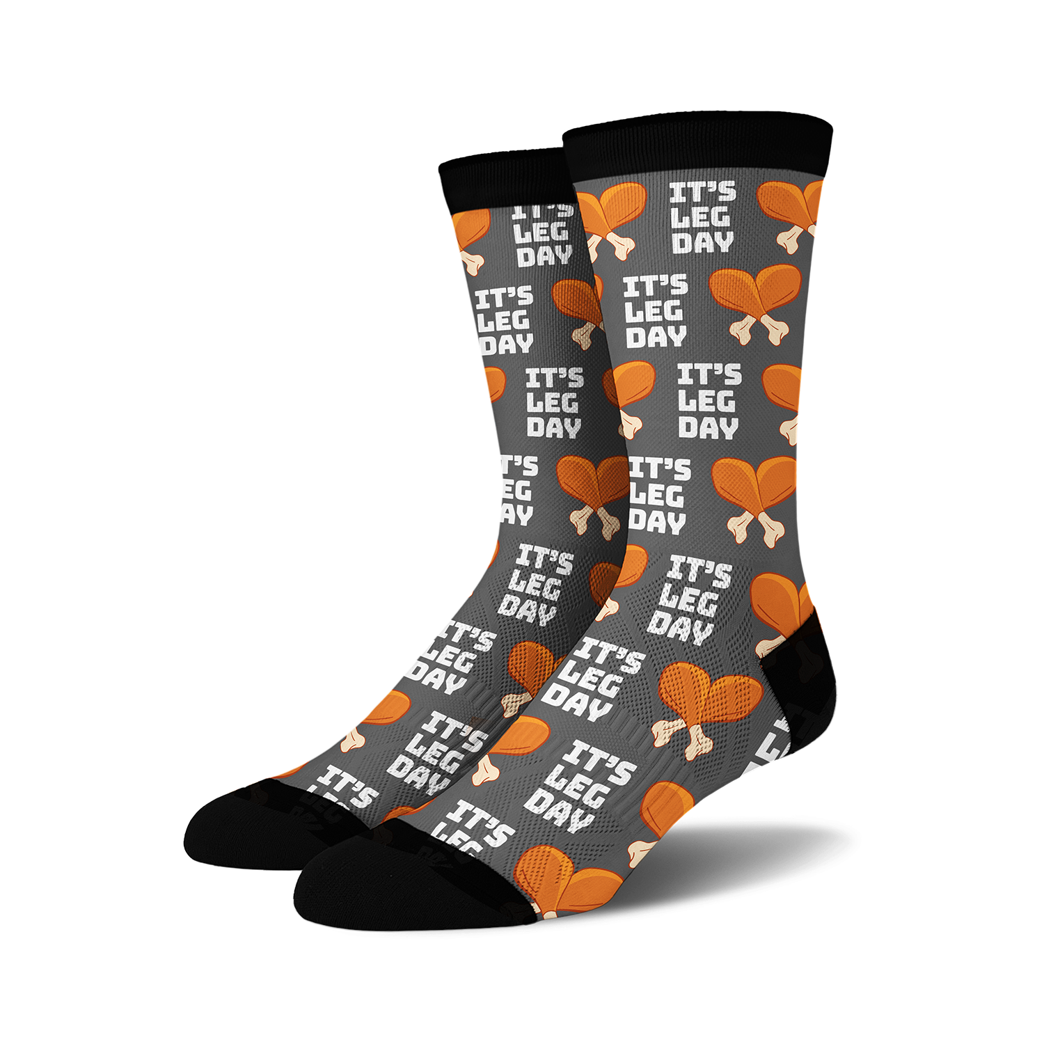 Pair of crew socks, dark grey with orange and white 'It's Leg Day' text and chicken leg illustrations repeating across the fabric.