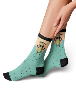 A pair of black socks with a green pattern of polka dots and a cartoon pickle wearing sunglasses giving the middle finger with the text 
