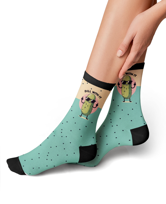 A pair of black socks with a green pattern of polka dots and a cartoon pickle wearing sunglasses giving the middle finger with the text 