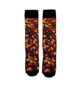 A pair of crew socks with an allover pattern of autumn leaves in orange, red, yellow, and brown on a black background.