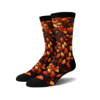 Pair of crew socks with an autumn leaves print.  The socks are predominantly dark brown with orange and red leaves.
