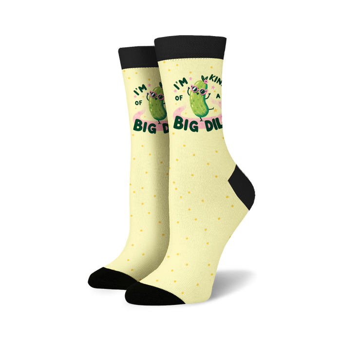 A pair of yellow socks with black toes, heels, and cuffs. The socks have a pattern of black polka dots and a cartoon illustration of a pickle wearing sunglasses and a pink bow. The pickle is surrounded by text that reads 
