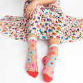 Person sitting in a floral dress wearing sheer socks with pink and blue flowers, with skin visible through the mesh fabric.