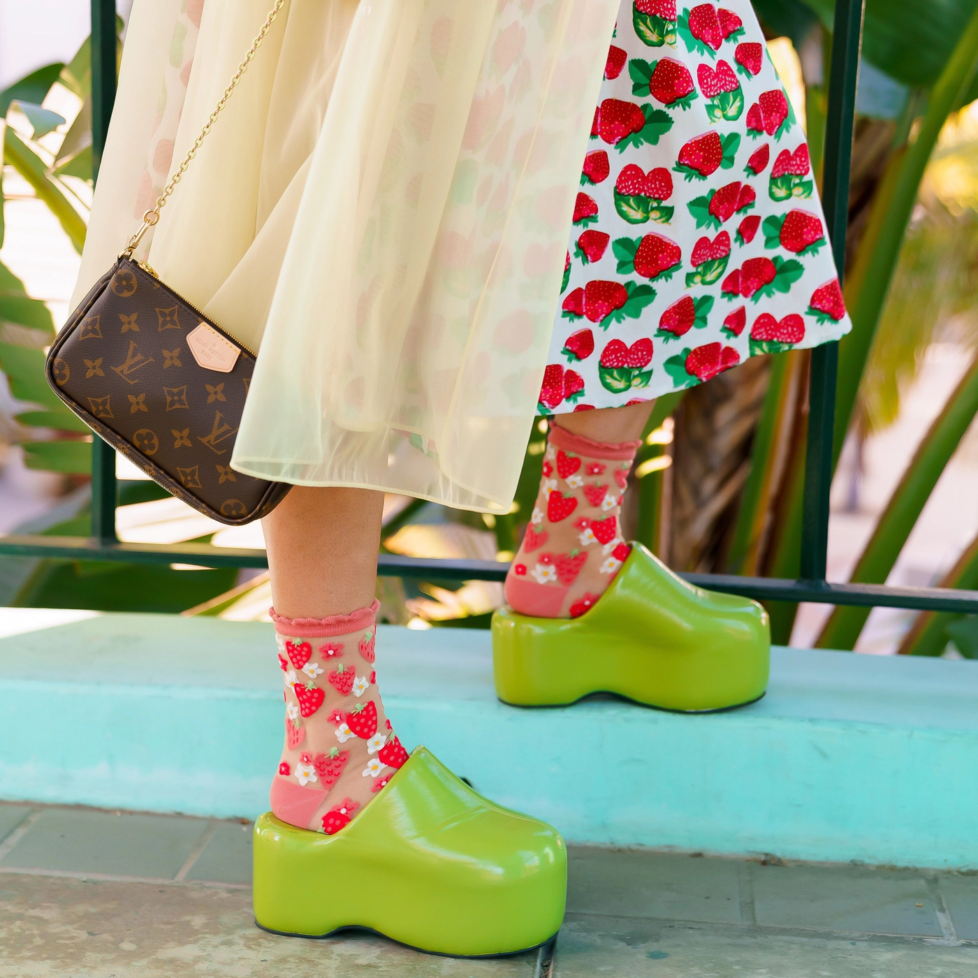 Detail view highlighting the transparent mesh fabric, bright red strawberries, and coral-pink ruffled ankle cuff.