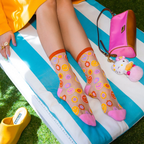 Legs crossed on a blue and white striped lounge chair wearing sheer smiley flower socks, next to a pink bag and cat plush.