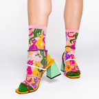 Person wearing sheer colorful cat socks with strappy block heels featuring green, yellow, and pink elements.