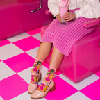 Close up of sheer sock material highlighting quirky, brightly colored cat faces in green, purple, yellow, and pink.