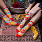 Sheer socks with yellow, teal, orange, and red flowers against a black background with solid red cuffs and toes.