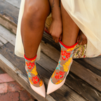 Close up of feet wearing sheer floral socks paired with matching floral pumps and pale pink pointed toe heels.