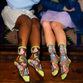 Close view of the lime green heel and toe details on the sheer dog pattern socks, worn by two people on a patterned rug.