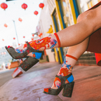 Pair of sheer mesh socks laid flat, showing intricate red and gold horse embroidery, vibrant florals, and blue heel accents.